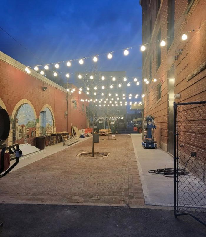 Festoon lighting over a brick courtyard beside Fortin & Gage and the Nashua Center for the Arts